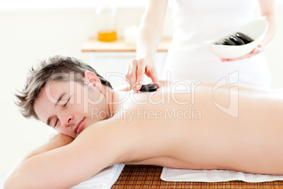 Charming young man receiving a massage with hot stone