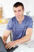 Handsome young man using his laptop looking at the camera