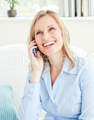 Joyful businesswoman talking on phone sitting on a sofa