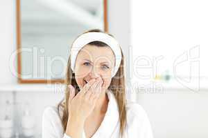 Tired young woman yawning in the bathroom looking at the camera