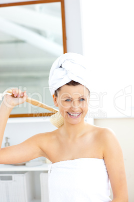 Lively woman washing her back smiling at the camera
