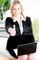 Postive businesswoman with thumb up using her laptop