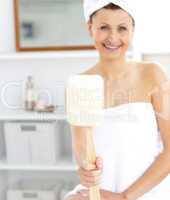 Merry woman holding a brush smiling at the camera