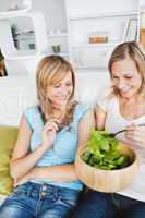 Cute young women eating a healthy salad at home