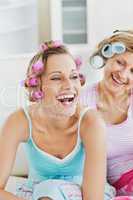 Laughing women wearing hair rollers sitting on the sofa