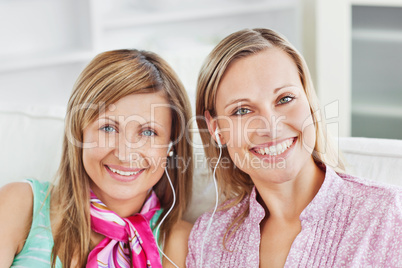 Captivating two female friends listen to music smiling at the ca