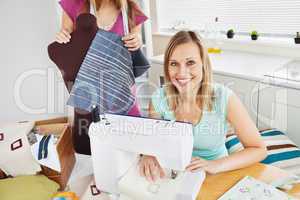 Smiling woman sewing in the kitchen with her friend