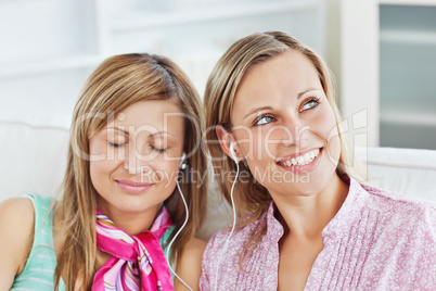 Relaxed two female friends listen to music sitting on a sofa