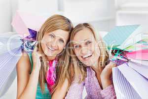 Glowing two women holding shopping bags smiling at the camera