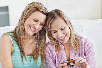Two gorgeous women using a digital camera at home