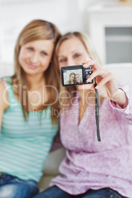Two gorgeous women using a digital camera at home