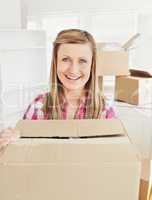 Positive woman holding a box standing in her new house looking a