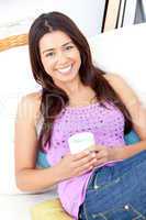 Bright woman holding a cup of coffee smiling at the camera