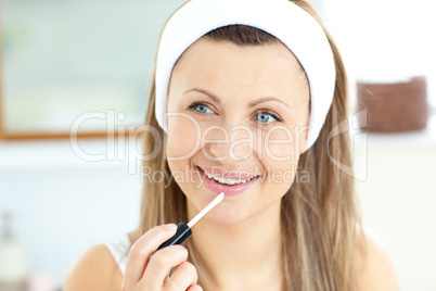 Attractive young woman using lipgloss in the bathroom