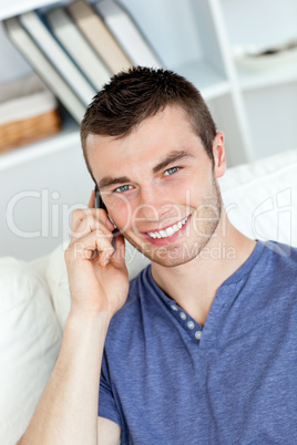 Happy young man talking on phone smiling at the camera