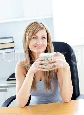 Relaxed woman holding a cup sitting on a chair at home