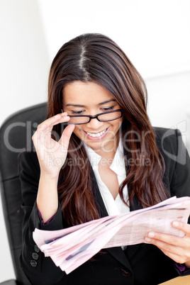 Confident young businesswoman reading newspaper