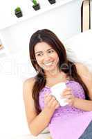 Relaxed woman holding a cup of coffee sitting on the sofa
