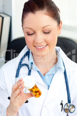 Smiling female doctor holding pills sitting in her office