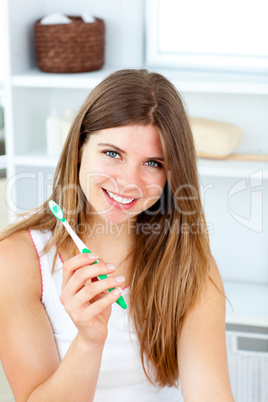 Delighted woman holding a toothbrush smiling at the camera