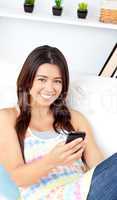 Glowing asian woman holding a cellphone smiling at the camera