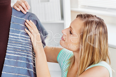 Concentrated young woman sewing clothes at home