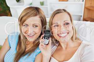 Two bright women using a cellphone at home