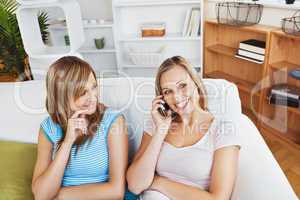 Two happy women using a cellphone at home