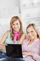 Two cheerful women using a laptop on the sofa