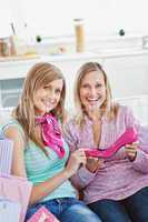 Two delighted women with shopping bags showing a pink shoe at ho