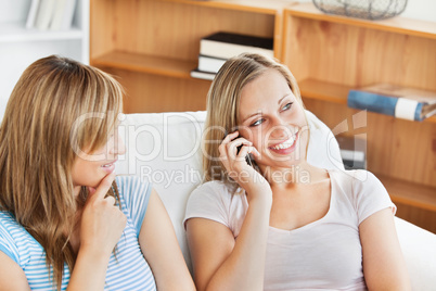 Two pretty women using a cellphone at home