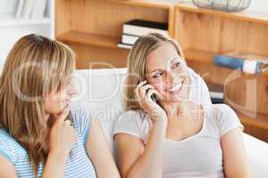Two pretty women using a cellphone at home