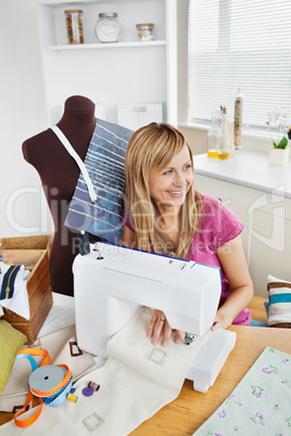 Delighted woman sewing clothes in the kitchen