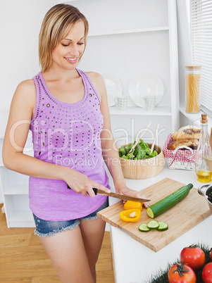 Concentrated woman cutting pepper and cucumber at home
