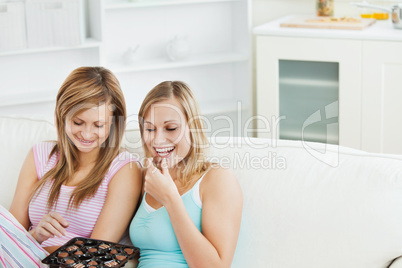 Two beautiful female friends eating chocolate at home