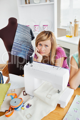 Depressed woman sewing clothes in the kitchen
