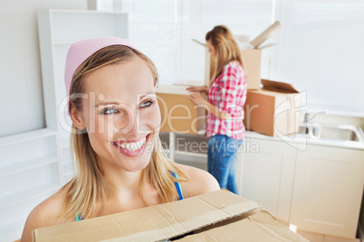 Two joyful women carrying boxes at home