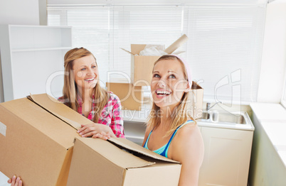 Two radiant women carrying boxes at home