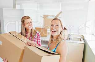 Two radiant women carrying boxes at home