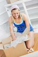 Charming woman unpacking a box on the floor