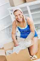 Attractive woman unpacking a box on the floor