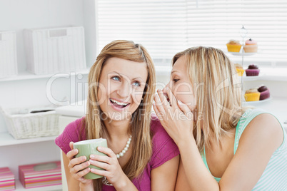 Close female friends talking together with a cup of coffee at ho