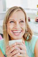 Laughing woman holding a cup of coffee at home