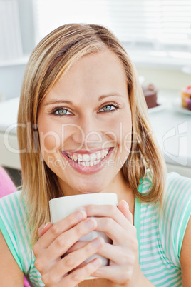 Glowing woman holding a cup of coffee at home