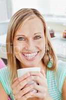 Glowing woman holding a cup of coffee at home