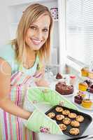 Smiling woman holding cookies in the kitchen