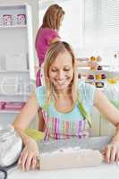 Cheerful woman baking together with her friend at home
