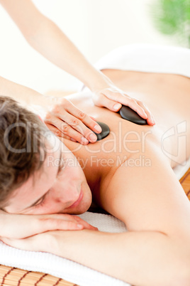 Resting man enjoying a massage with hot stone