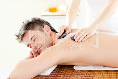 Charming man enjoying a massage with hot stone