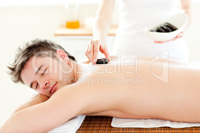 Smiling young man receiving hot stone on his back